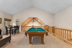 A pool table in a room with a sloped ceiling, a dining table with chairs, and a wooden railing. - Pine Lodge Chalet - Games Rm, Hot Tub, Dogs OK (Big Bear)