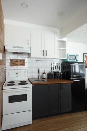 A kitchen with white cabinets, a stove, a sink, and a vintage-style refrigerator. - Condo cosy ski-in/ski-out - village piétonnier (Mont-Tremblant)