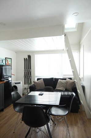 A compact living space with a dining table, chairs, a sofa, a ski rack, and a ladder. - Condo cosy ski-in/ski-out - village piétonnier (Mont-Tremblant)