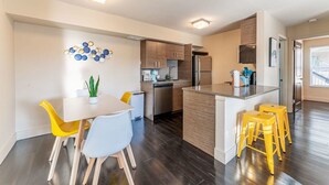 A modern kitchen with a central island, wooden cabinets, and a stainless steel refrigerator. - Charming 2BR King Beds Suite Next to DT w Pool (Austin)