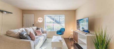 A living room with a sofa, coffee table, TV, and a plant.
