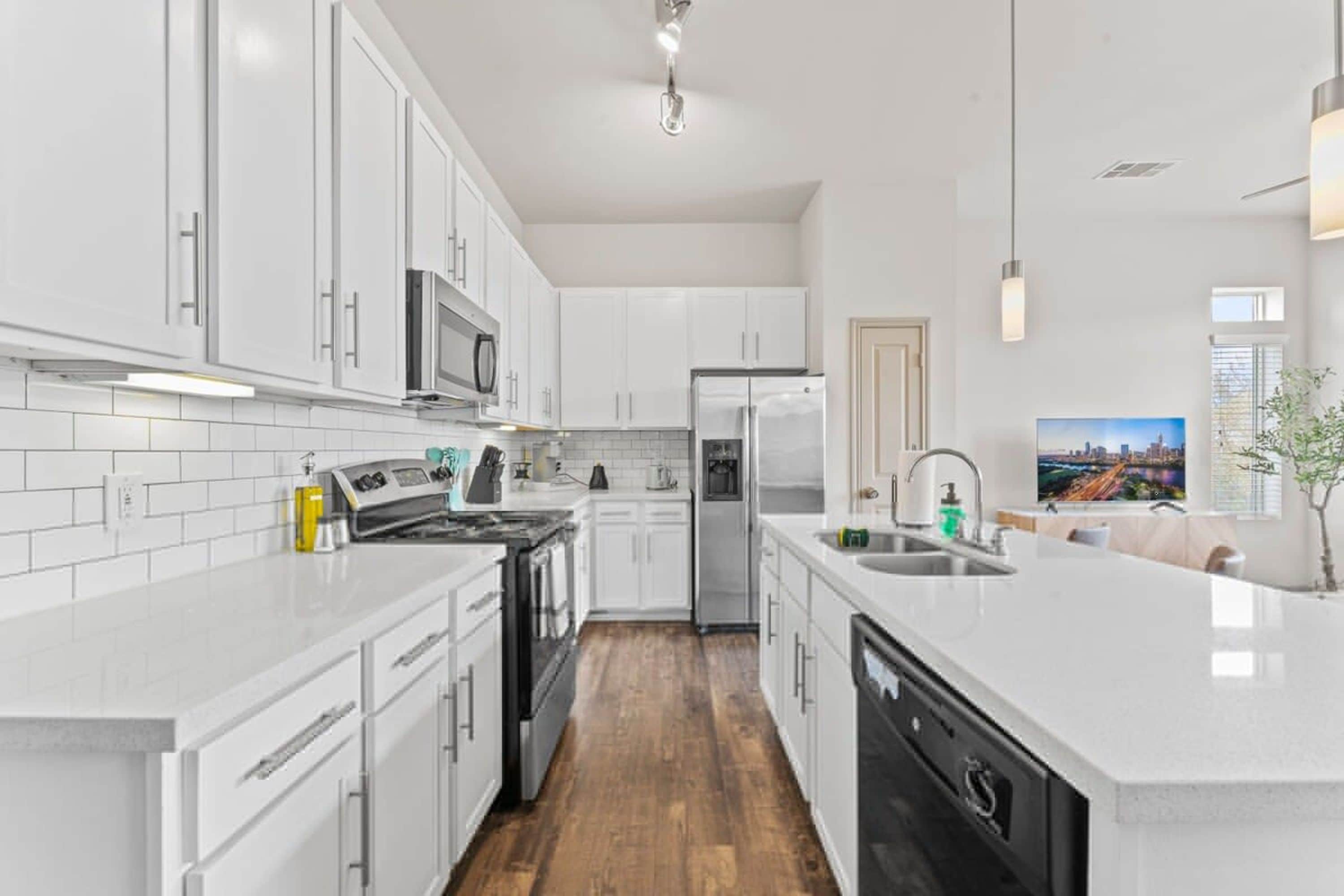 Una cocina moderna con armarios blancos, electrodomésticos de acero inoxidable y una isla central con fregadero.