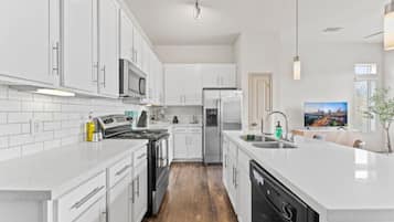 Una cocina moderna con armarios blancos, electrodomésticos de acero inoxidable y una isla central con fregadero.