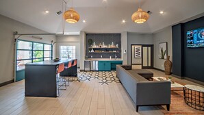 A modern kitchen with a bar area, a dining table, and a sofa in a spacious living area with a patterned floor. - Bright 2BR King Suite w Gym Close to Downtown (Austin)