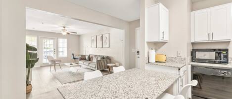 A modern kitchen with granite countertops, white cabinetry, and stainless steel appliances.