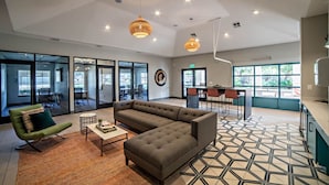 A modern interior with a sectional sofa, a green armchair, a coffee table, and a patterned floor. - Bright 2BR King Suite w Gym Close to Downtown (Austin)