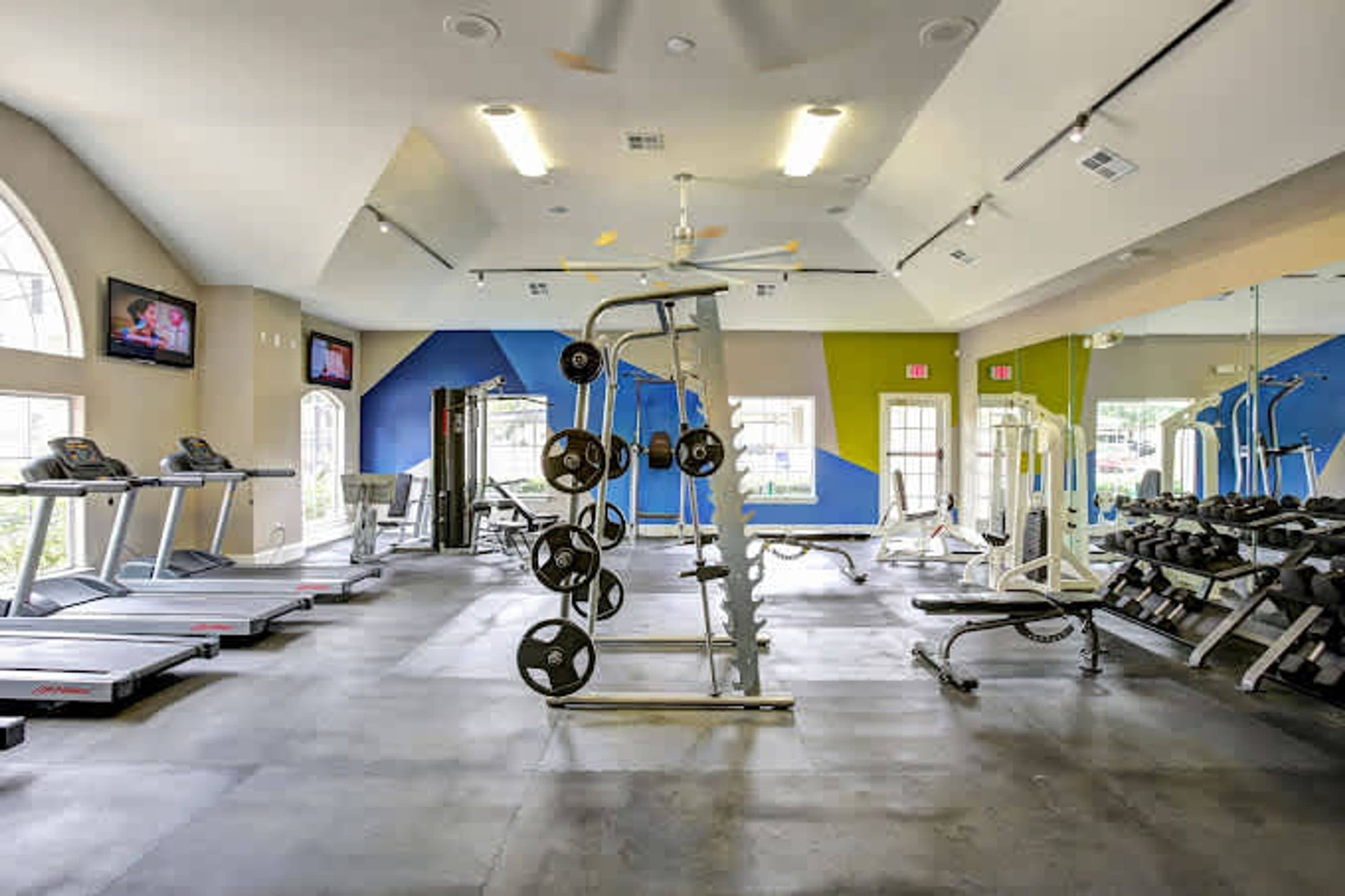 Une salle de sport équipée de tapis de course, de matériel de musculation et d’appareils d’exercice.