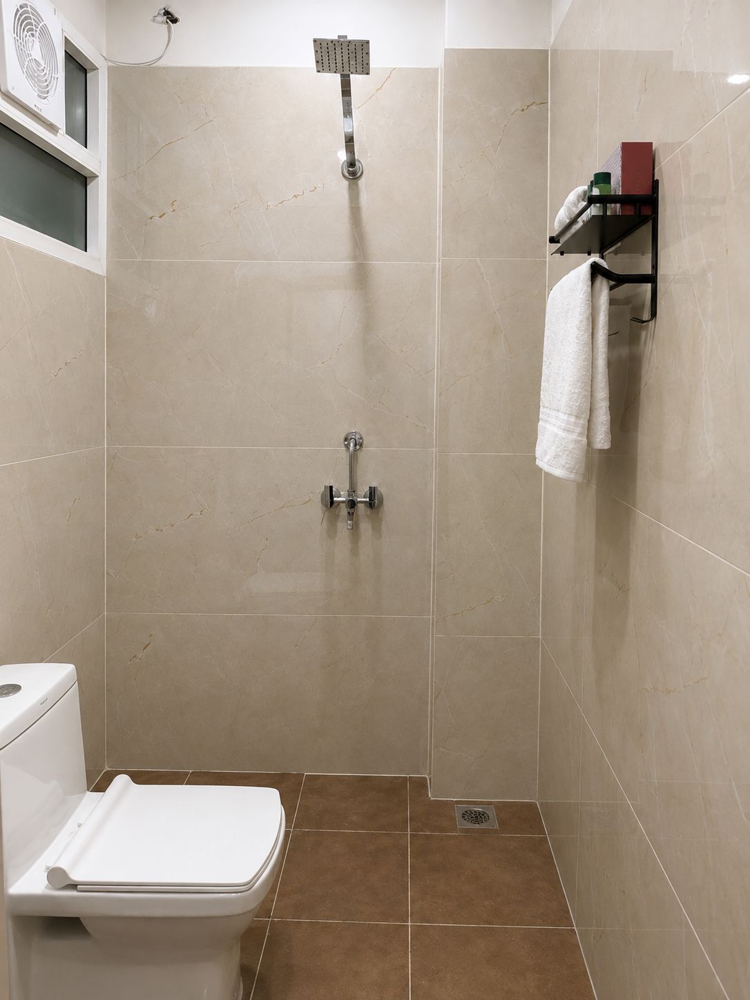 Een badkamer met douche, toilet en handdoekrek.
