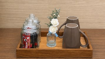 Ein Holzbahn mit einem Glasbehälter, einer kleinen Vase mit weißen Blumen und einer braunen Tasse.