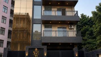 A multi-story building with a modern architectural design, featuring balconies, a gated entrance, and a sign indicating 'VINTAGE VAULTS PREMIUM STAY.'