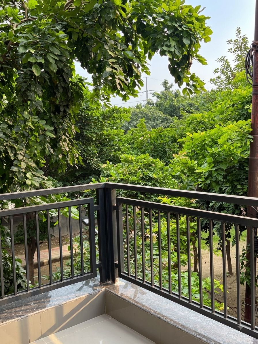A balcony with a metal railing overlooking a garden with various trees and shrubs.