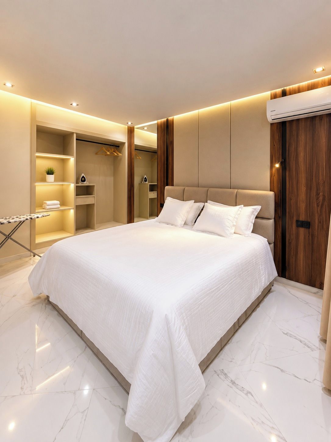 Une chambre à coucher moderne avec un grand lit, une armoire intégrée et une coiffeuse avec un miroir.