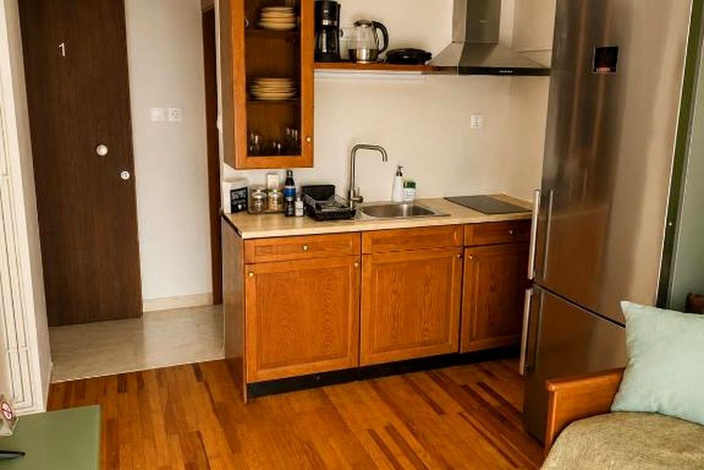 A compact kitchen with wooden cabinets, a stainless steel refrigerator, and a sink.