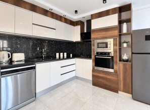 Una cocina moderna con electrodomésticos de acero inoxidable, encimera de granito negro y armarios de madera.