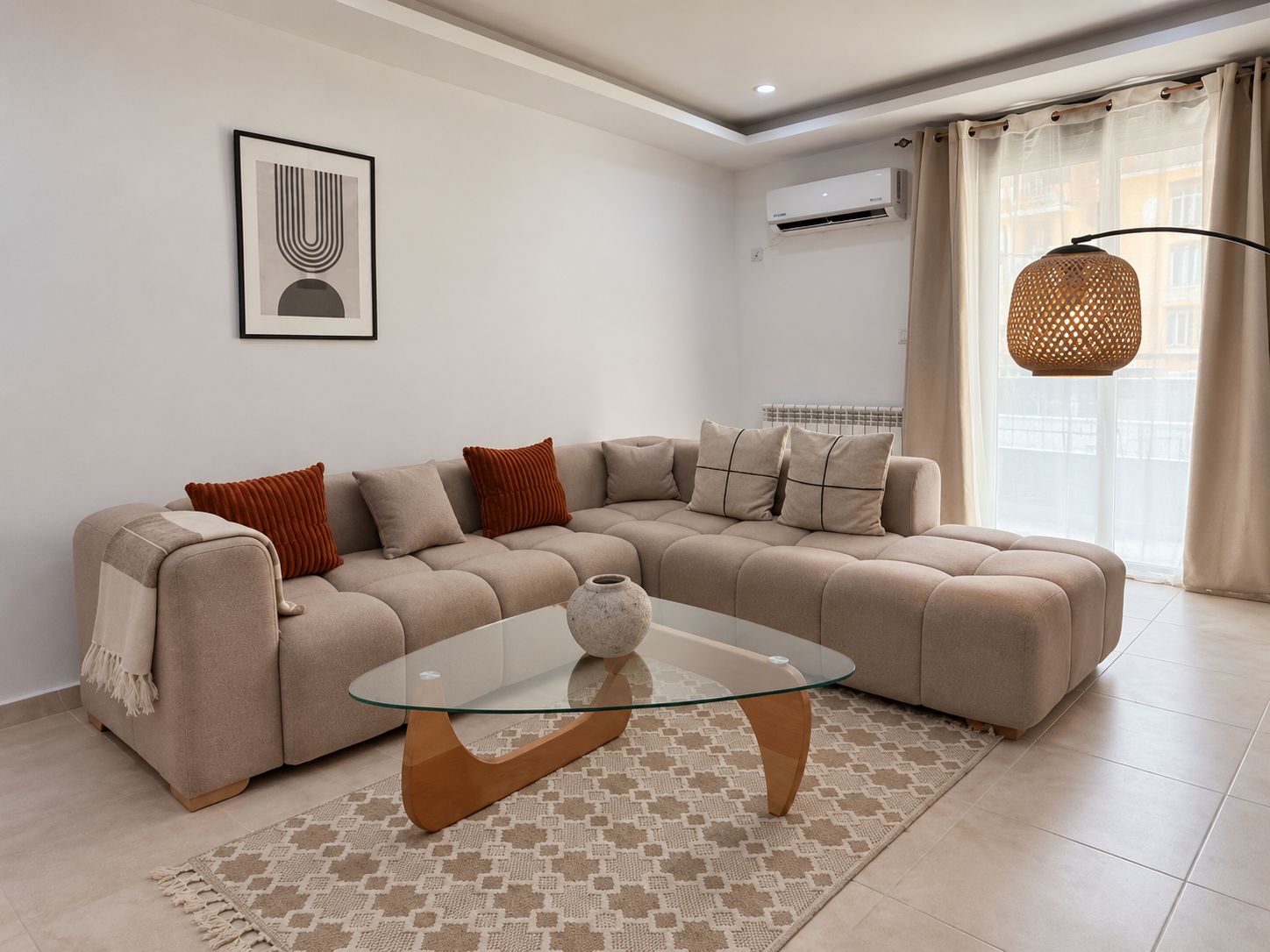 A modern living room with a sectional sofa, a glass coffee table, and a patterned rug.