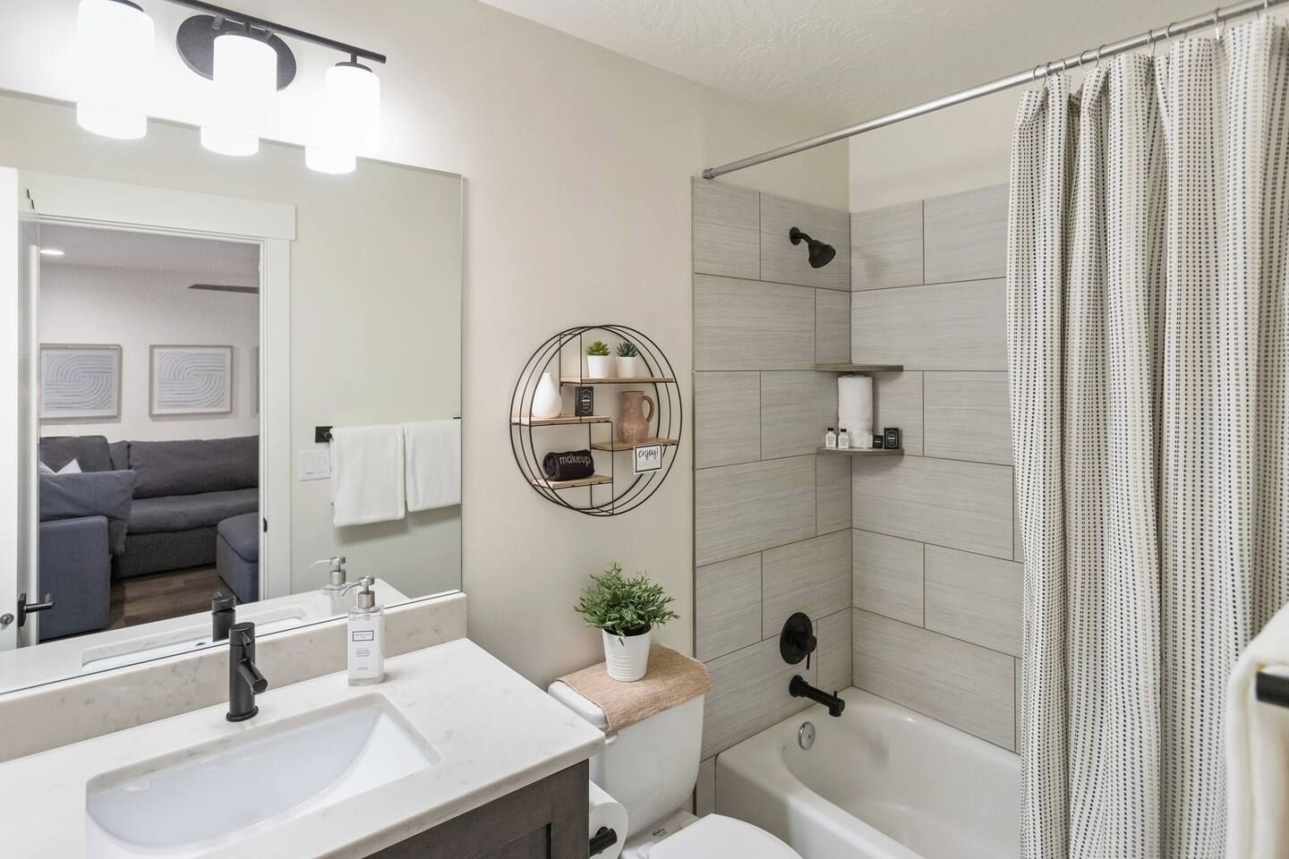 Un baño moderno con lavamanos, espejo y ducha.