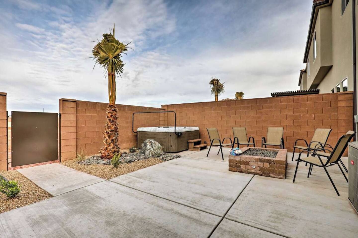 An outdoor patio with a barbecue grill, seating area, and a palm tree.