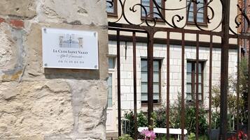Un bâtiment avec une enseigne indiquant « Le Clos Saint Vaast – Gîte et événements » et un portail en fer forgé.