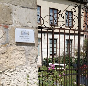 Un bâtiment avec une enseigne indiquant « Le Clos Saint Vaast – Gîte et événements » et un portail en fer forgé.