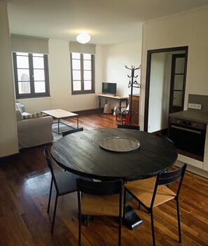 Un coin repas avec une table ronde, des chaises et un porte-manteau.