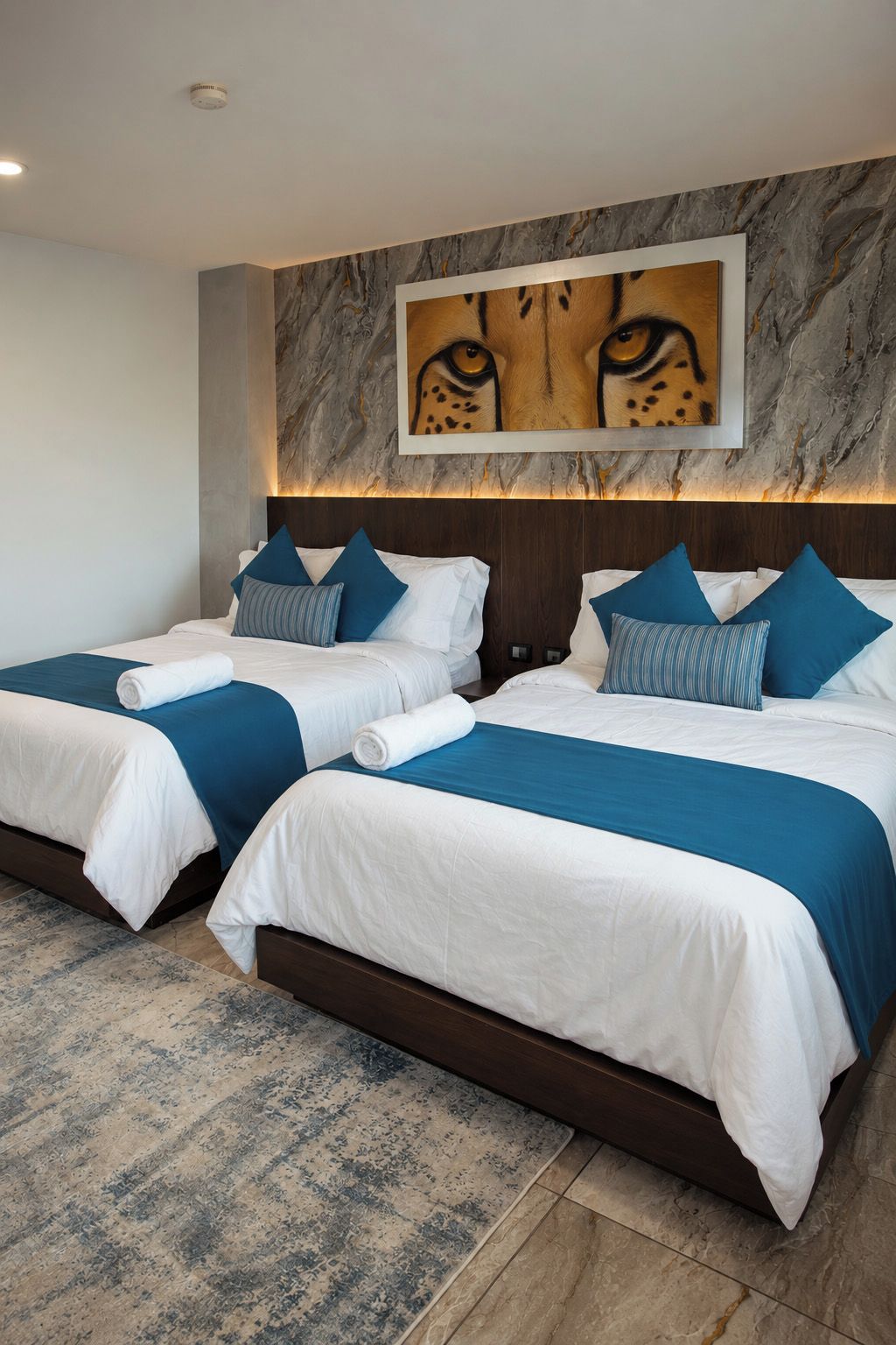 Habitación de hotel con dos camas, detalles decorativos de mármol en la pared y una alfombra estampada.