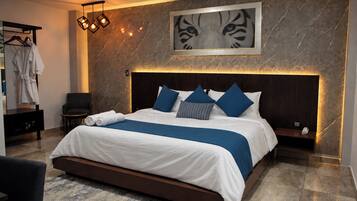 Una habitación de hotel moderna con una cama grande, un cabecero con iluminación integrada, una pared de mármol y una obra de arte enmarcada sobre la cama.