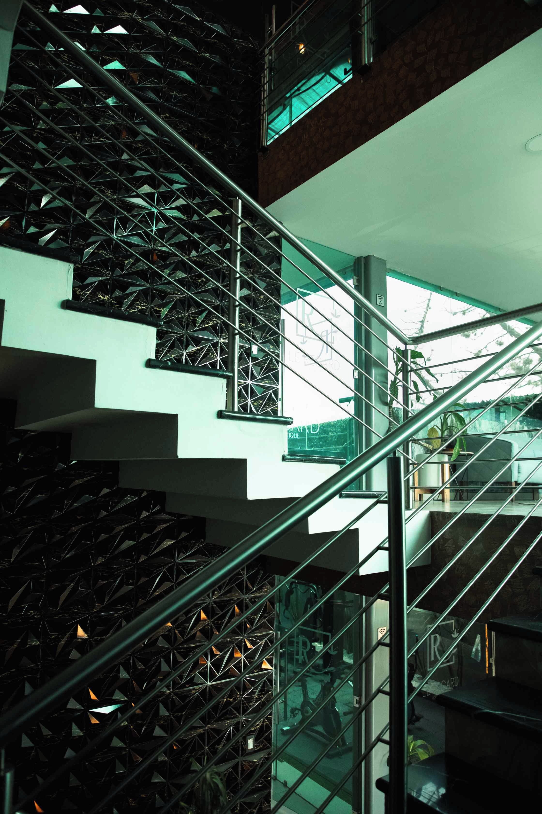 Un interior de varios niveles con escalera, barandillas de vidrio y un diseño moderno.