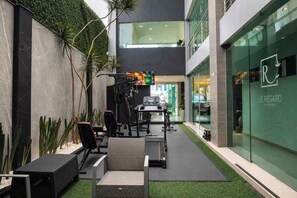 Un área de estar exterior moderna con una mesa de comedor, sillas y un pequeño jardín.