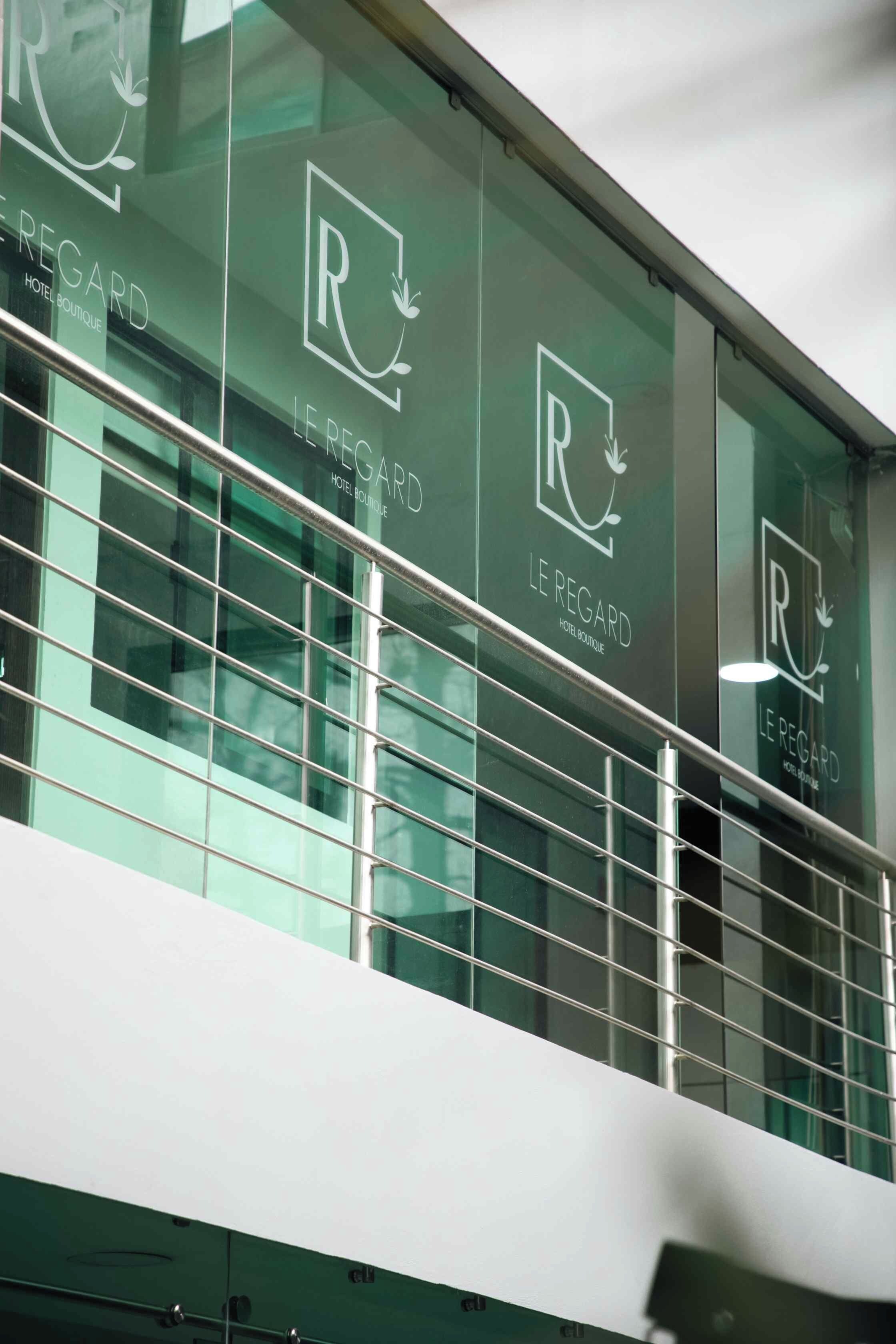 Fachada de edificio con múltiples ventanas que muestra el logo 'Le Régard Hotel Boutique'.