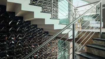 Un escalier moderne avec des rampes en verre et des balustrades en métal, menant aux différents niveaux du bâtiment.