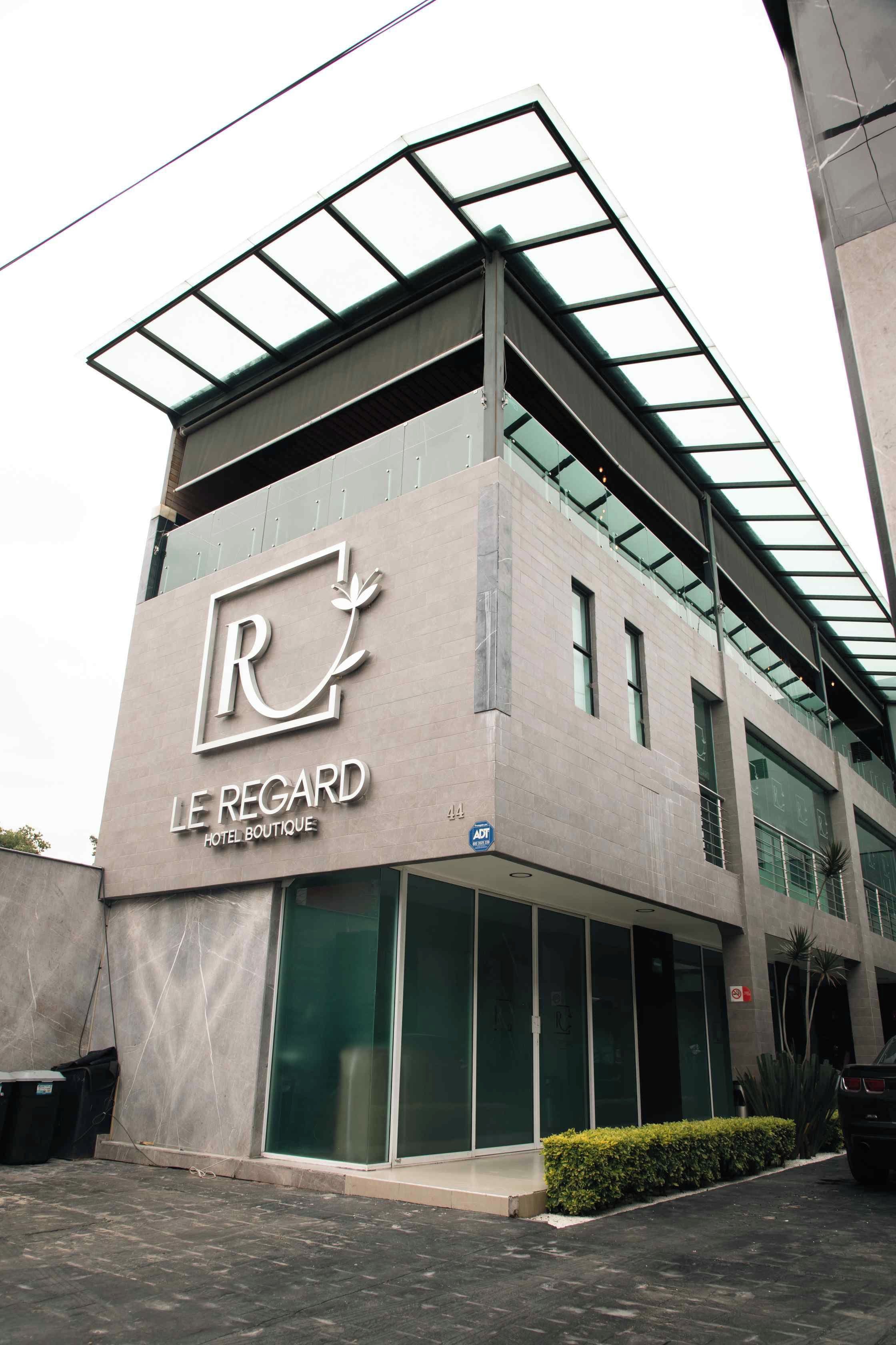 Un moderno edificio de hotel con un logotipo y señalización destacados para 'Le Régard Hotel Boutique'.