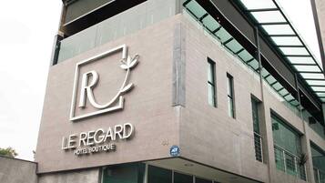 Un moderno edificio de hotel con un logotipo y señalización destacados para 'Le Régard Hotel Boutique'.