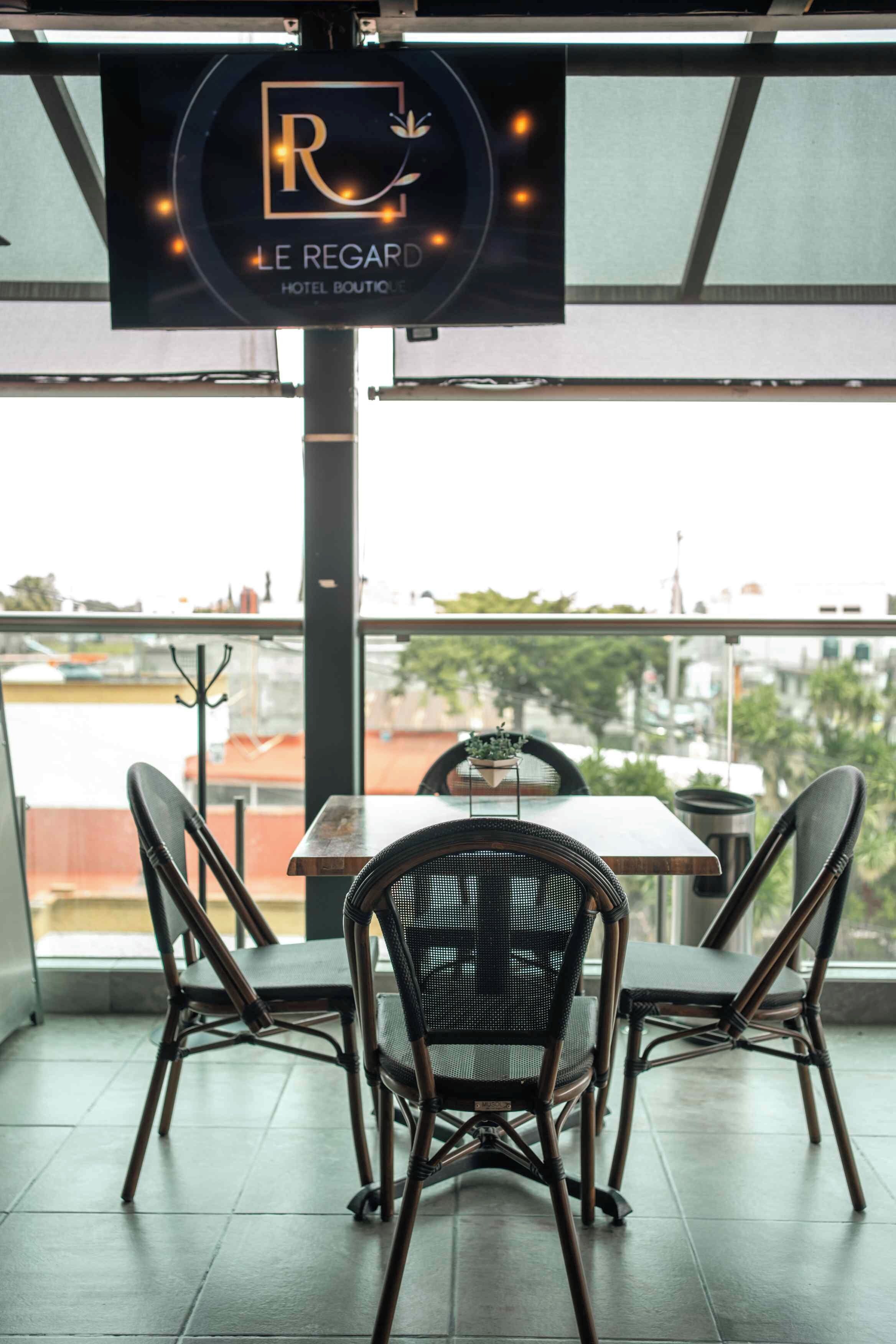 Un restaurante con vistas, que cuenta con una mesa y sillas, y un letrero que indica que es 'LE REGARD HOTEL BOUTIQUE'.