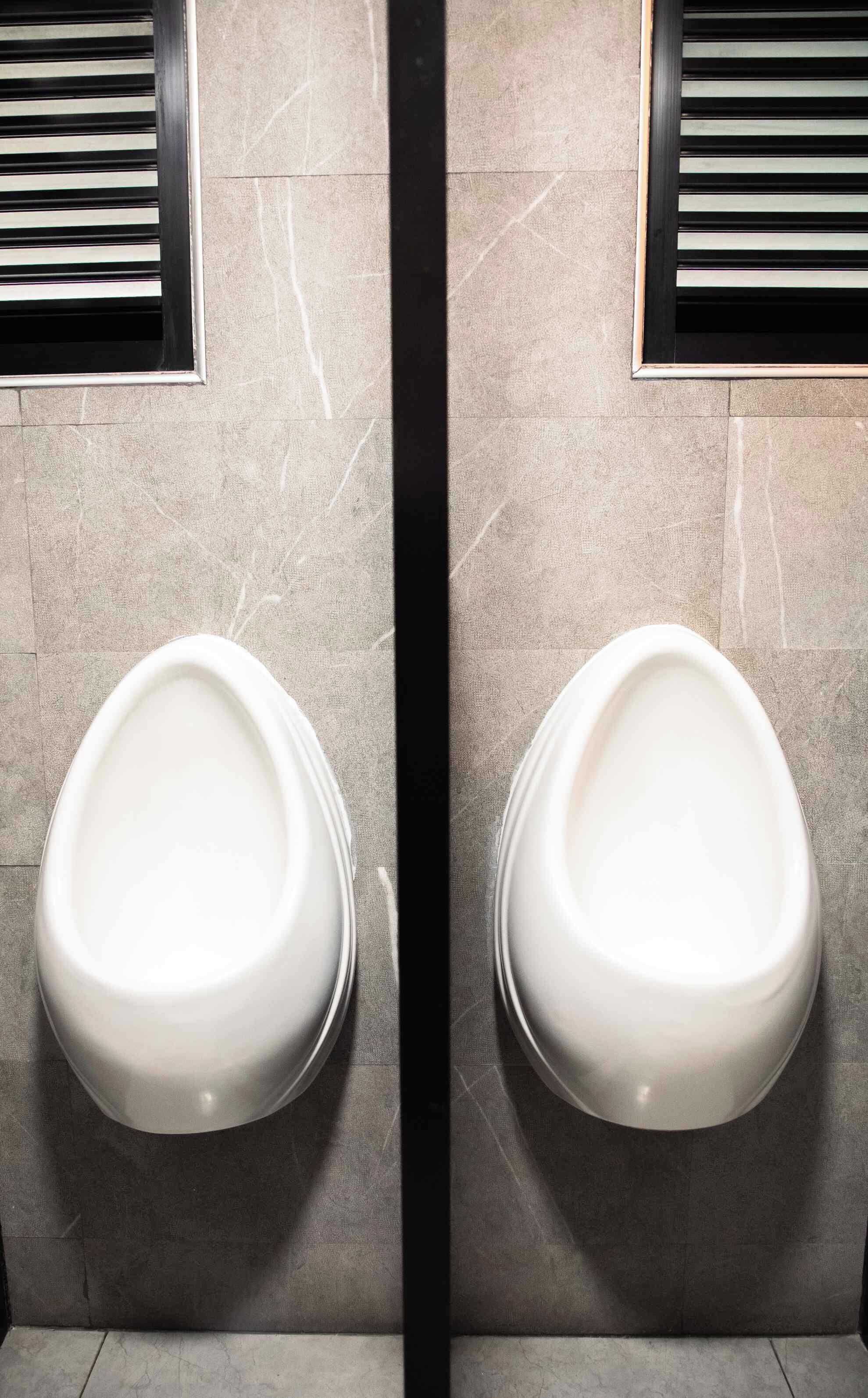 Baño con dos orinales instalados en una pared de azulejos.