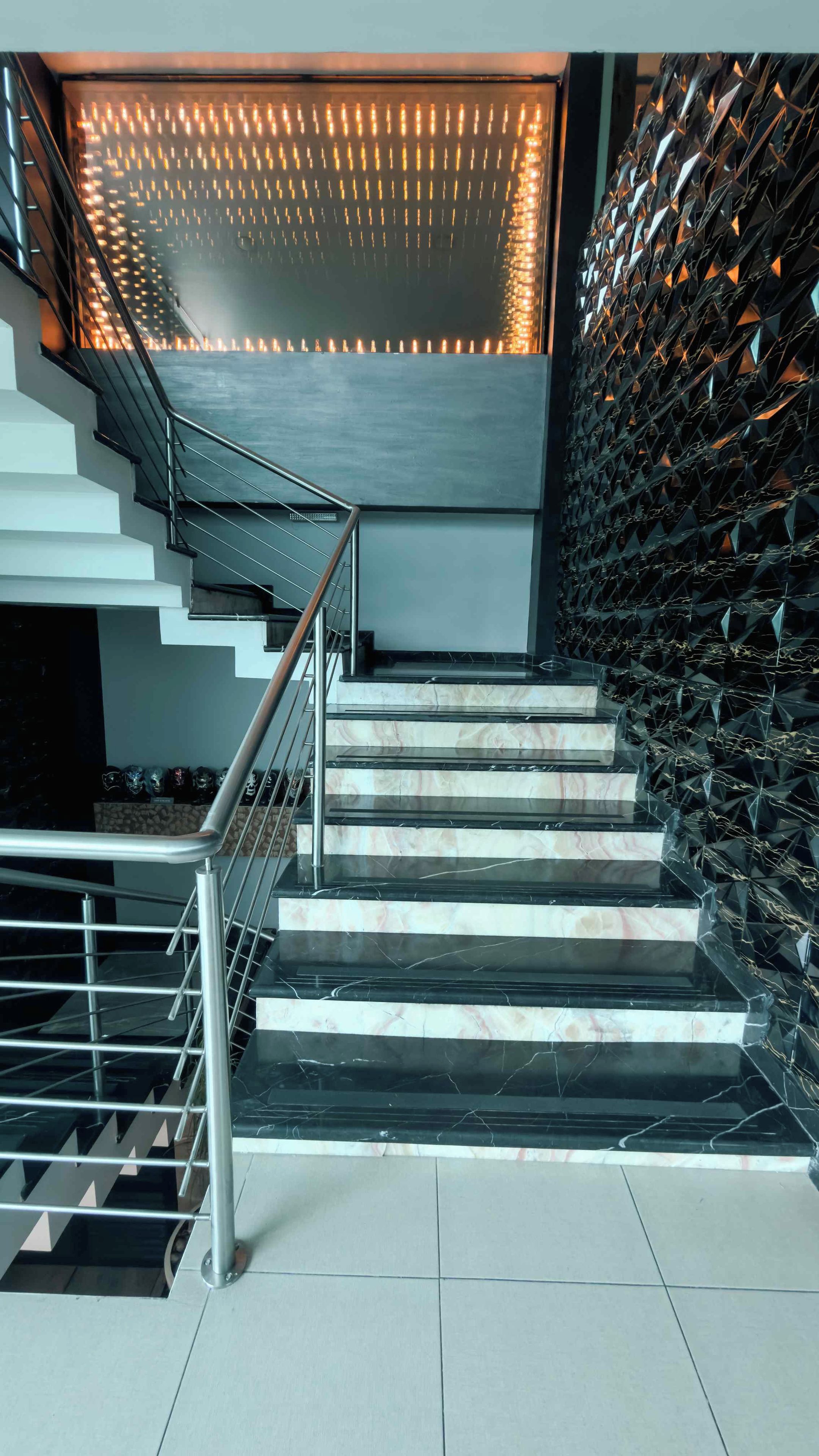 Una escalera moderna con barandilla de metal que conduce a una pared con un diseño geométrico.