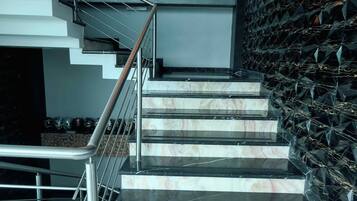 Una escalera moderna con barandilla de metal que conduce a una pared con un diseño geométrico.