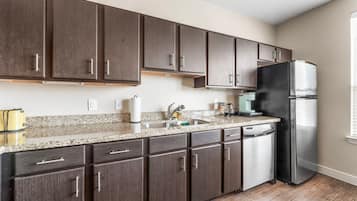 Una cocina moderna con armarios de madera oscura, un refrigerador de acero inoxidable y una encimera de granito.
