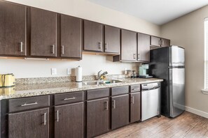 A modern kitchen with dark wood cabinets, a stainless steel refrigerator, and a granite countertop. - Chic Soco 1BR King Suite w Gympickleballlaundry (Austin)