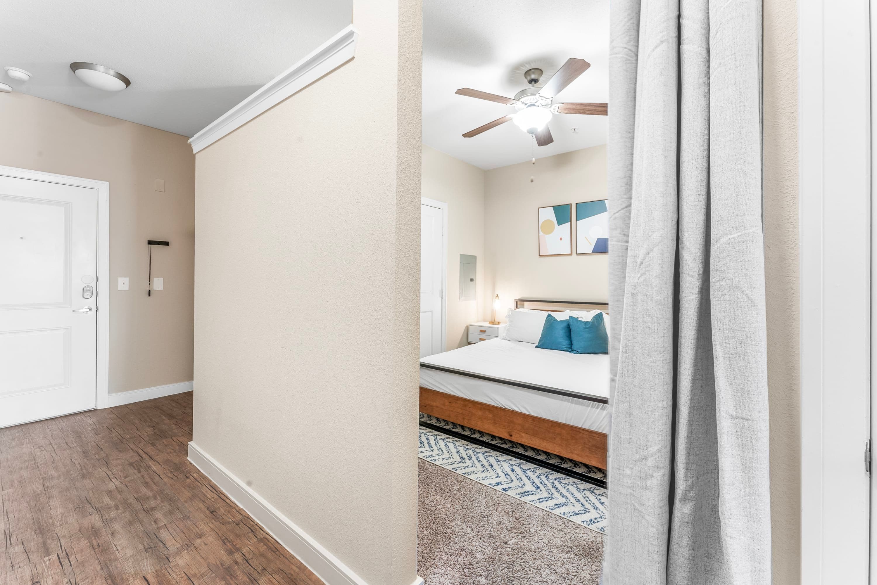 A bedroom with a bed, a ceiling fan, and a nightstand.