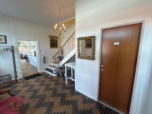 A hotel lobby with a staircase, a chandelier, a mirror, and a door labeled 'Toilet'. - kroen ved åen (Skive)