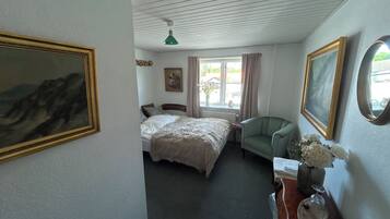 A bedroom with a bed, a chair, a dresser, and a window with curtains.