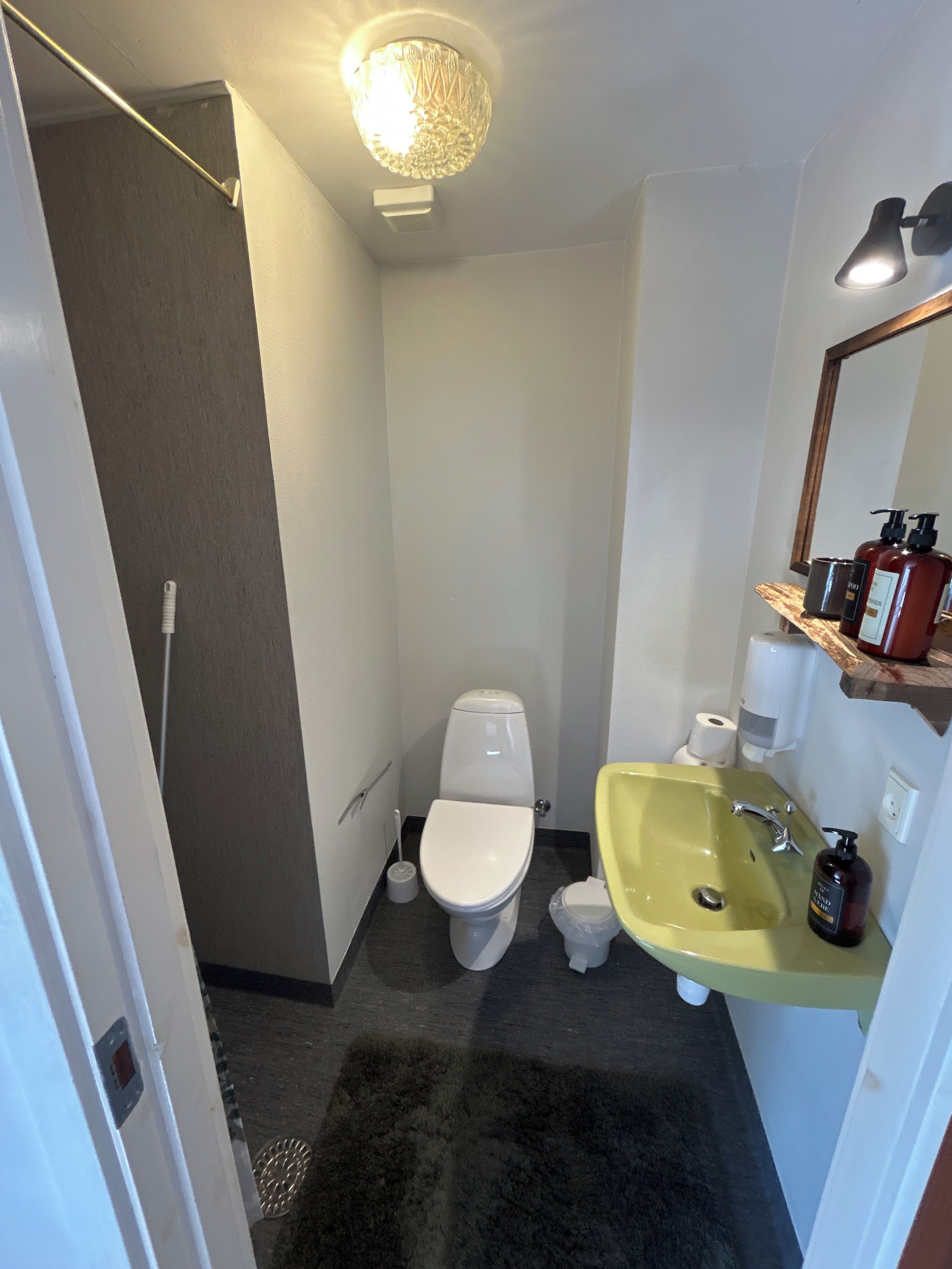 Un baño pequeño con inodoro, lavamanos y espejo.