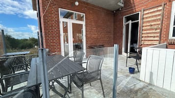 Un patio con mesa y sillas, una puerta corrediza de vidrio y un edificio de ladrillo.
