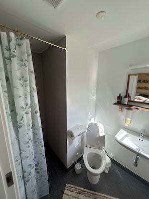 A modern bathroom with a toilet, sink, and shower curtain. - kroen ved åen (Skive)