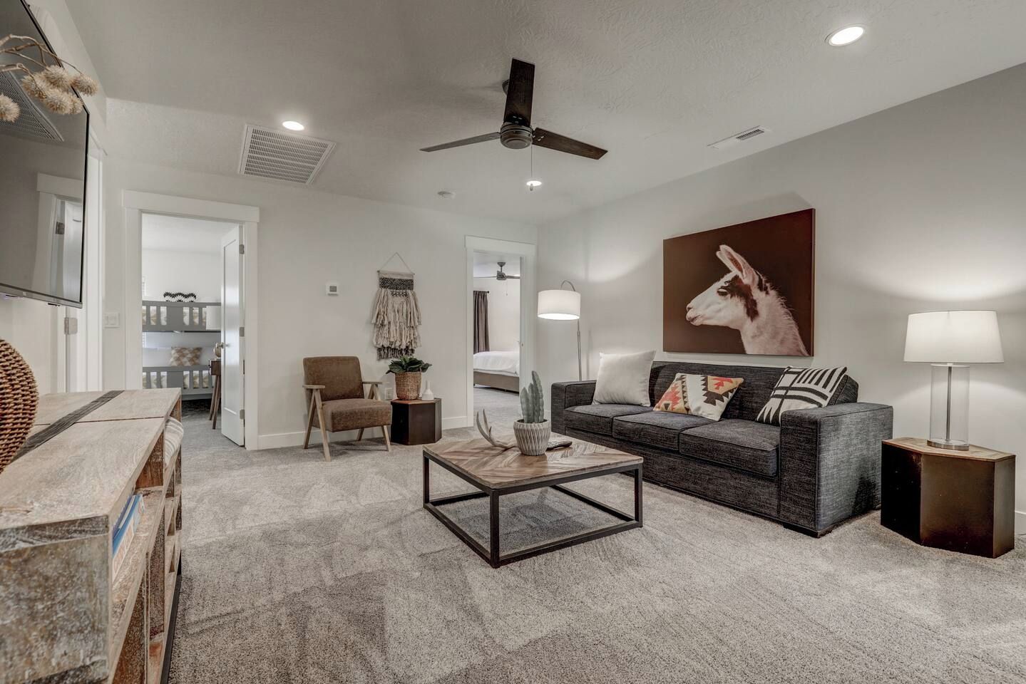 A modern living room with a sofa, armchair, coffee table, and a ceiling fan.