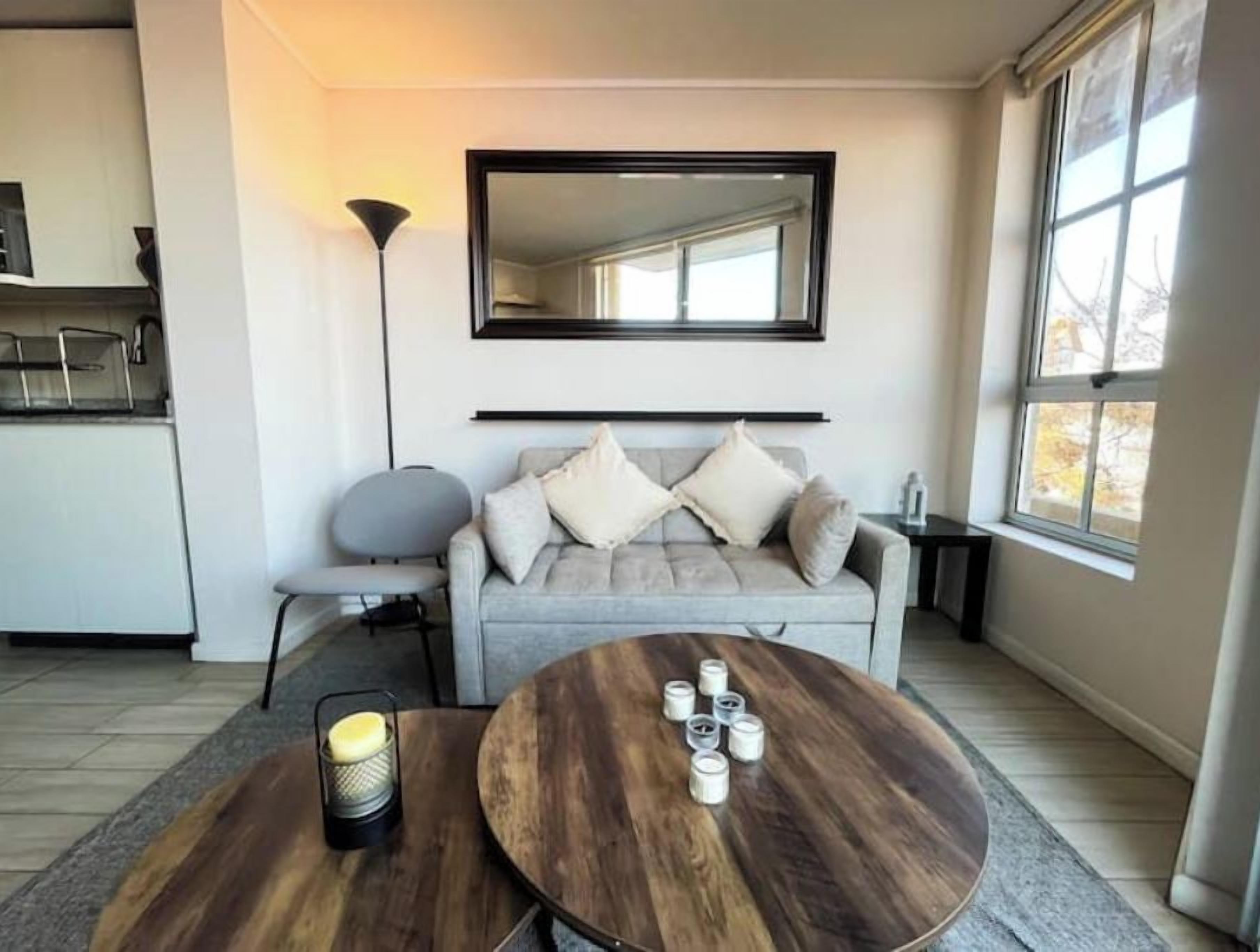 A modern living room with a sofa, a coffee table, a lamp, and a large window.