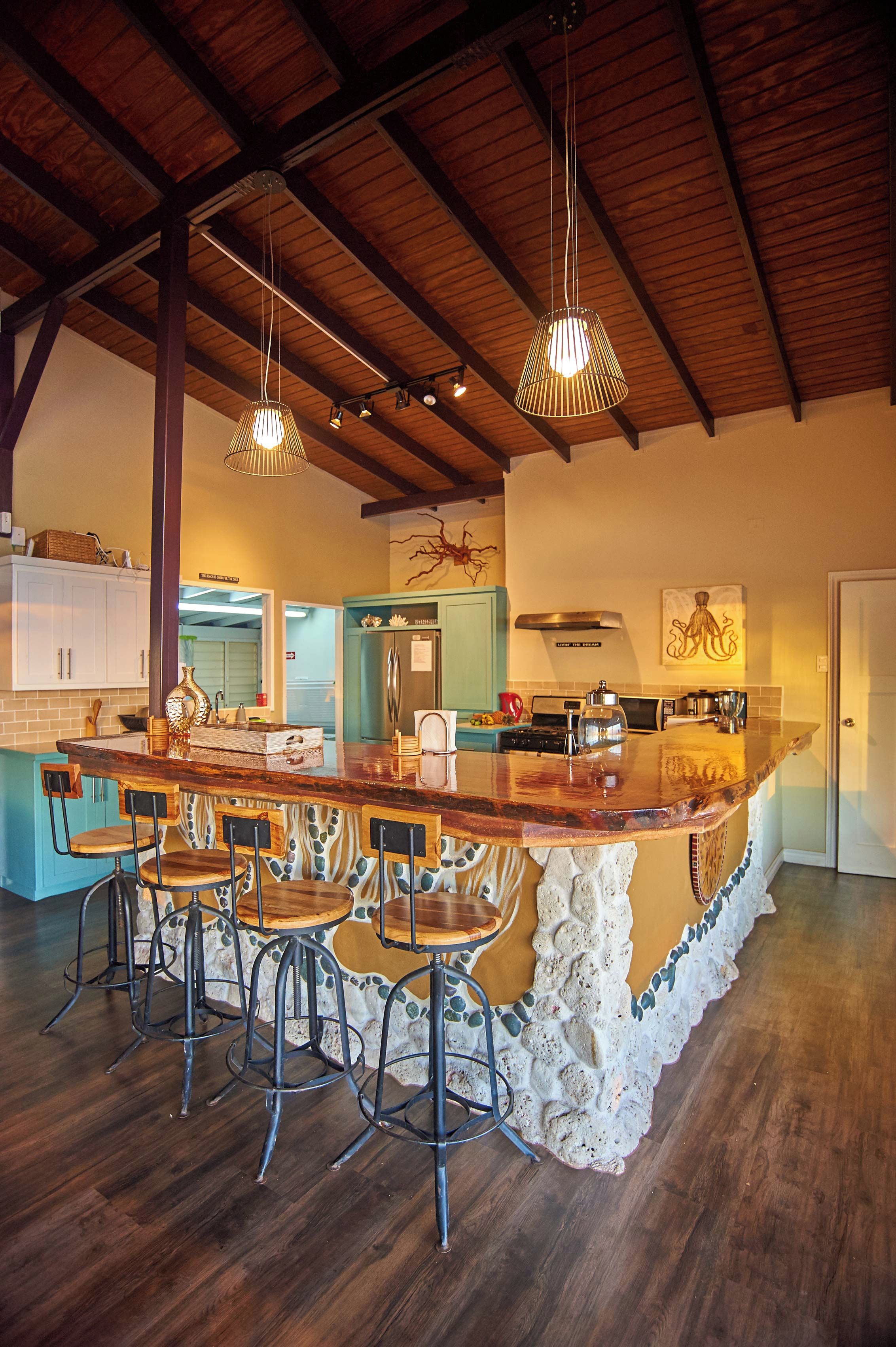 A spacious kitchen with a large island, bar stools, and pendant lighting.