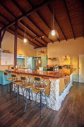 A spacious kitchen with a large island, bar stools, and pendant lighting.