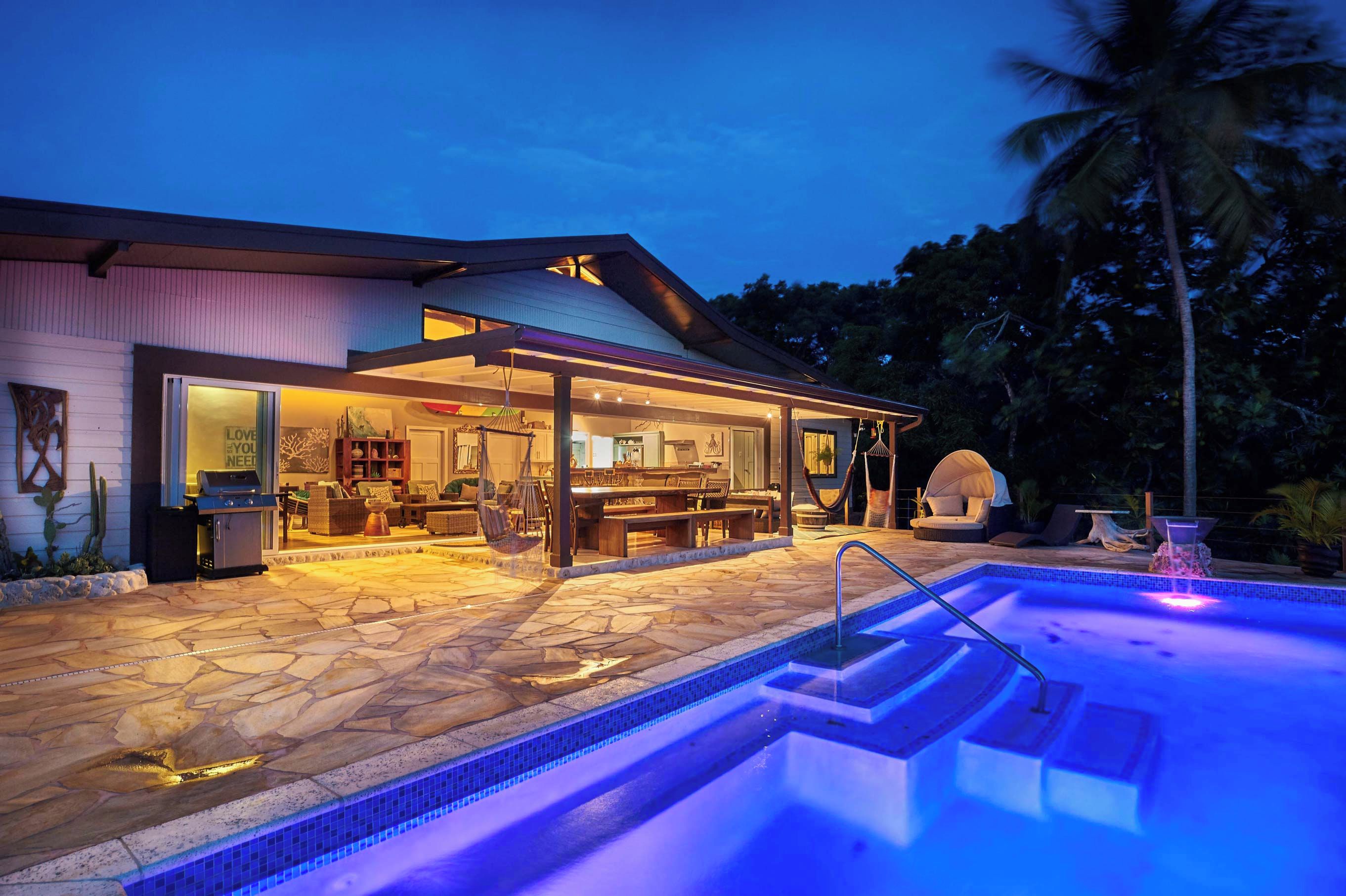 A modern house with a swimming pool, outdoor seating, and a covered patio area.