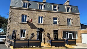A multi-story building with a stone facade, a restaurant sign, and a bench in front. - Vrbo Property (Vicq-sur-Mer)